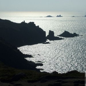 A silhouetted view of Land's End and Longships beyond.