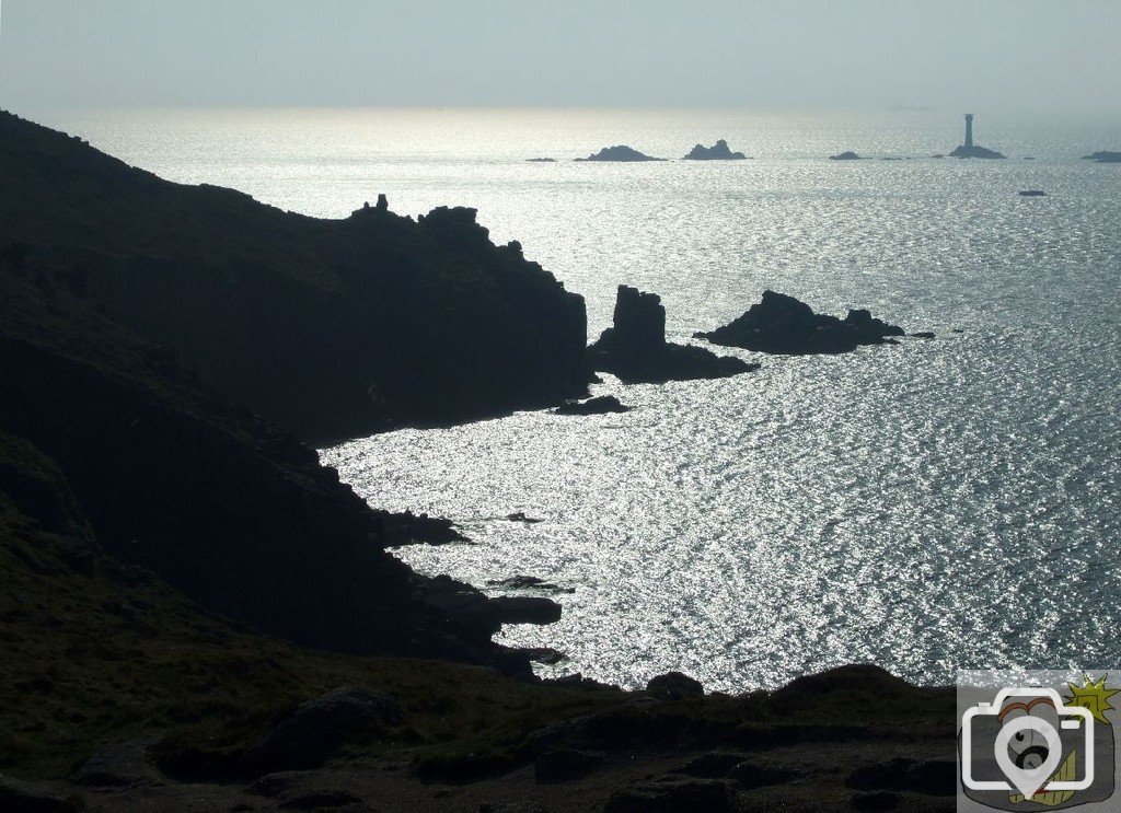 A silhouetted view of Land's End and Longships beyond.